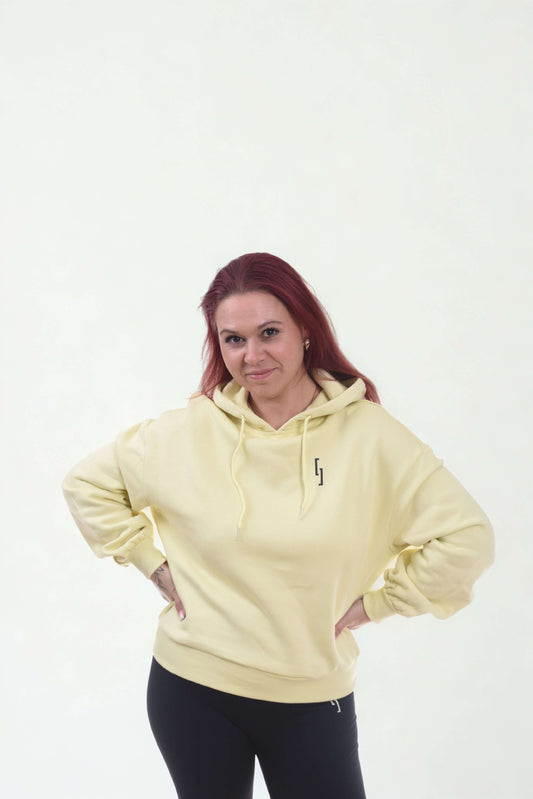 Model wearing a cropped oversized hoodie in yellow from the Raw Line collection.