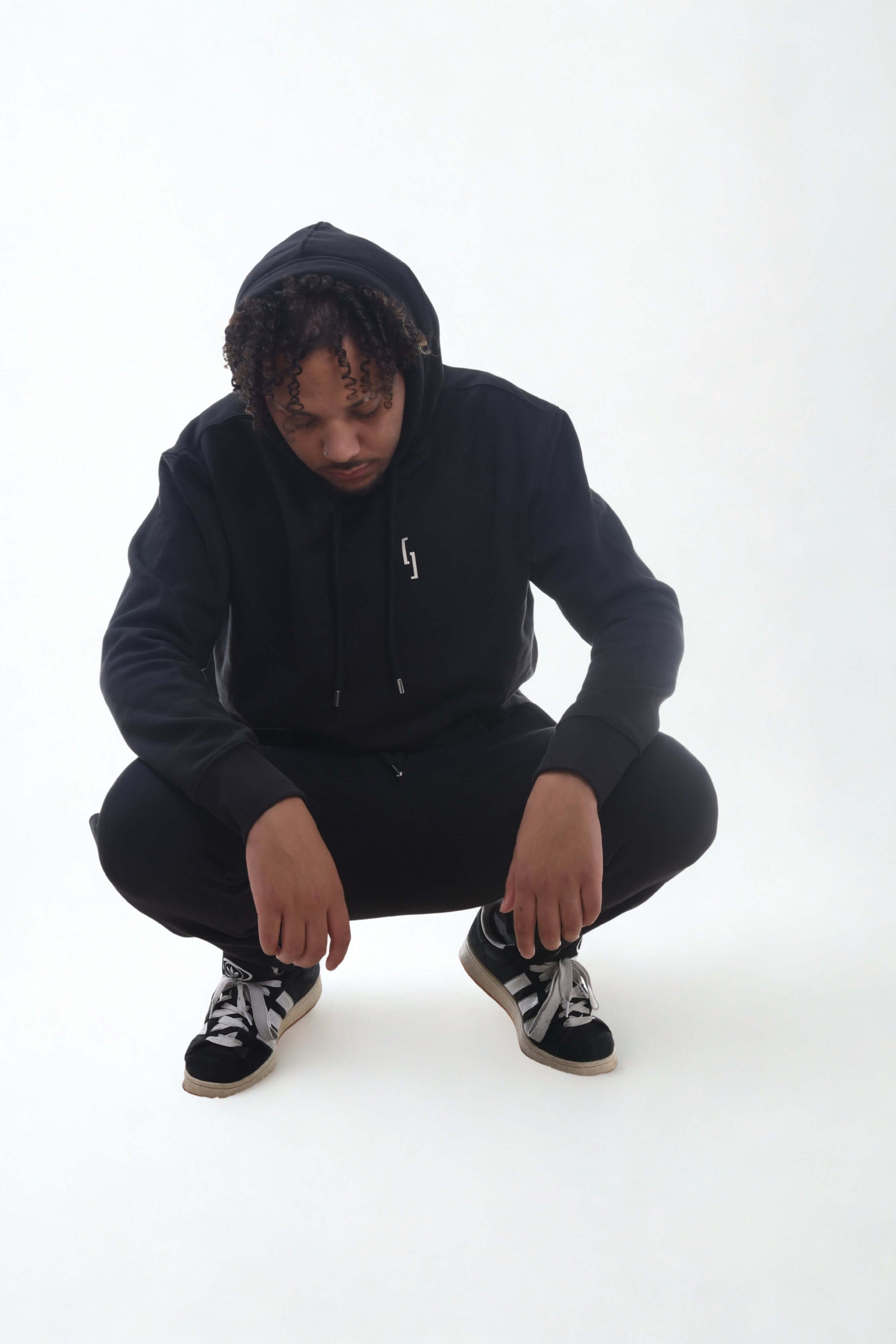 Heavyweight hoodie - Raw Line worn by a model in a low crouch, showcasing its stylish, slim fit and comfortable design.