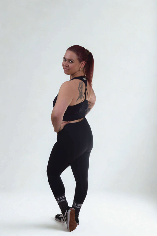 Woman modeling a performance sports bra - RAW FORGED with leggings, showcasing fitness style and confidence.