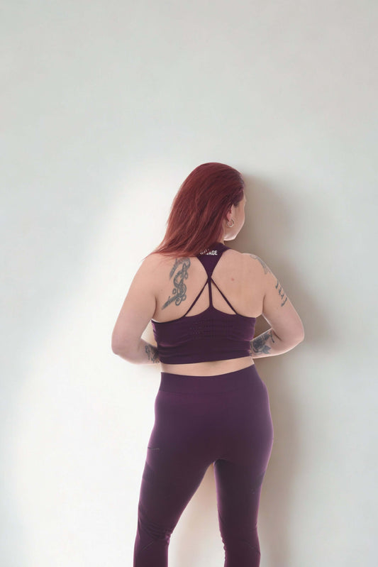 Woman wearing PERFORMANCE LEGGINGS - RAW FORGED in purple, showcasing stylish design and tattoos from a back view.