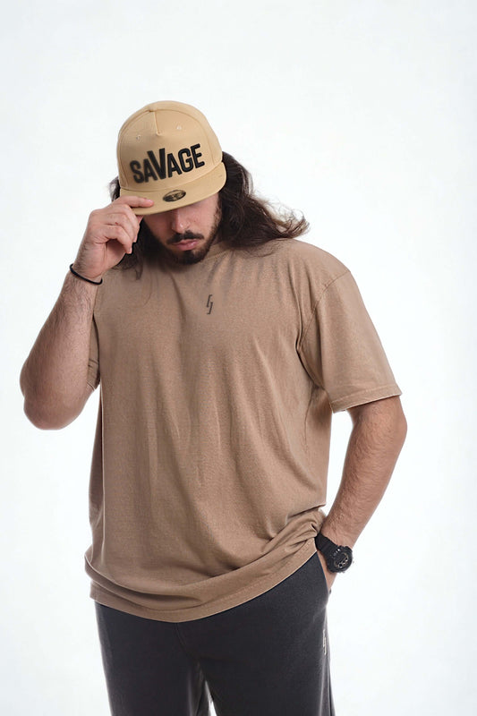 Model wearing a vintage oversized shirt in beige, paired with a SAVAGE cap, showcasing a relaxed, stylish look.